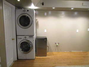 Second Laundry room with hardwood / wood-style floors and stacked washer / drying machine