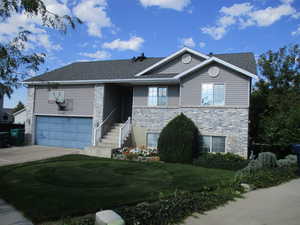 View of front facade featuring a garage and a front lawn