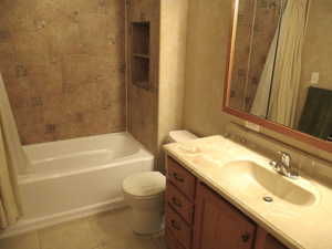 Full bathroom in basement featuring vanity, toilet, shower / tub combo, and tile patterned flooring