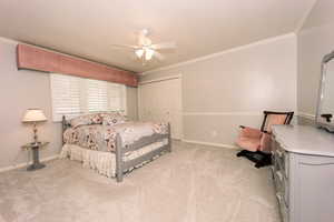 Bedroom featuring crown molding, light colored carpet, ceiling fan, and a closet