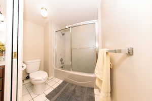 Full bathroom featuring tile patterned flooring, toilet, enclosed tub / shower combo, and vanity