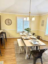 Dining space with light wood-type flooring, ornamental molding, vaulted ceiling, and plenty of natural light