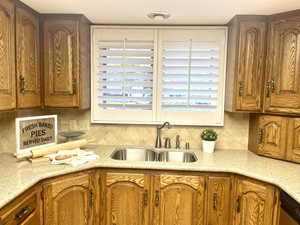 Kitchen with stainless steel dishwasher, tasteful backsplash, sink, and light stone countertops