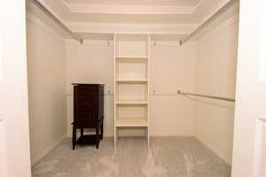 Primary bedroom aalk in closet with carpet floors