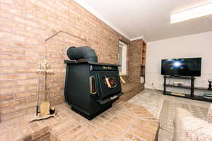 Carpeted living room with crown molding and brick wall