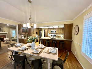 Dining space featuring ornamental molding, dark wood-type flooring, a fireplace, and an inviting chandelier