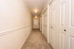 Corridor featuring crown molding and light carpet