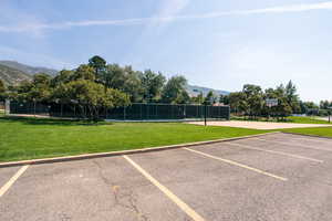 View of vehicle parking with a mountain view, a lawn, and basketball court