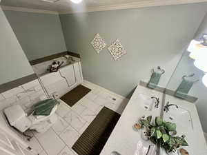 Bathroom with sink, crown molding, and toilet