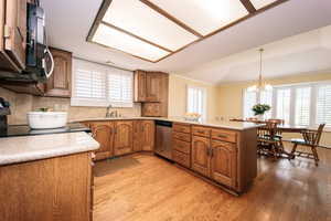 Kitchen with light hardwood / wood-style flooring, stainless steel appliances, an inviting chandelier, and kitchen peninsula