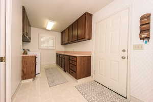 Laundry room with  dark brown cabinetry and washer/clothes dryer