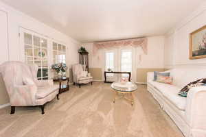 Living room featuring light carpet, french doors, and ornamental molding