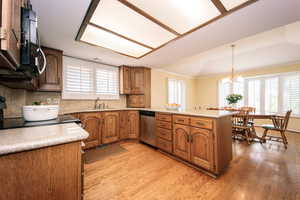 Kitchen featuring stainless steel appliances, kitchen peninsula, an inviting chandelier, sink, and light hardwood / wood-style floors