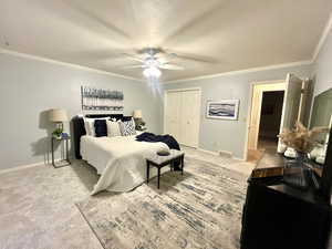 Carpeted bedroom with ornamental molding, a closet, and ceiling fan