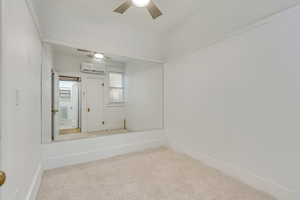 Carpeted room with a wall mounted AC, ceiling fan.