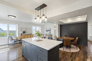 Kitchen with a raised ceiling, dark wood-type flooring, pendant lighting, a kitchen island, and a textured ceiling