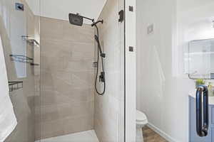 Bathroom featuring tiled shower, toilet, and hardwood / wood-style floors