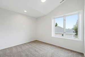 Carpeted empty room with vaulted ceiling and a wealth of natural light