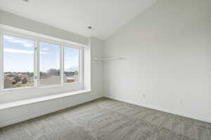 Empty room featuring lofted ceiling and light colored carpet