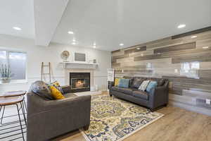 Living room featuring a textured ceiling, a tiled fireplace, wooden walls, and light hardwood / wood-style floors