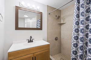 Bathroom featuring a shower with shower curtain, a textured ceiling, and vanity