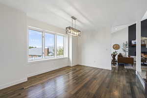 Unfurnished dining area featuring an inviting chandelier, a fireplace, dark hardwood / wood-style flooring, and a textured ceiling