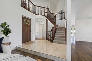 Entrance foyer with high vaulted ceiling and hardwood / wood-style flooring