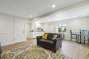 Living room with a textured ceiling, light hardwood / wood-style flooring, and sink