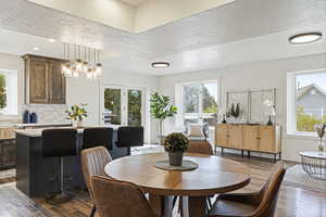 Dining area featuring dark wood-type flooring, a chandelier, and a textured ceiling