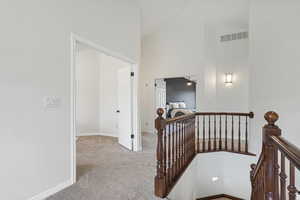 Hall featuring high vaulted ceiling and light colored carpet