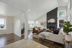 Living room with hardwood / wood-style floors, high vaulted ceiling, and a fireplace