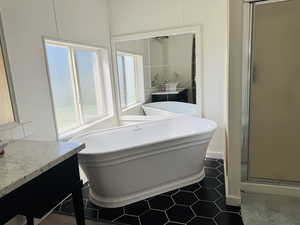 Full bathroom featuring vanity, a freestanding bath, a shower stall, and tile patterned floors