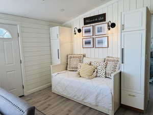 Bedroom featuring wood finished floors and wood walls