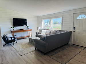 Living room featuring wood finished floors, lofted ceiling, and wooden walls