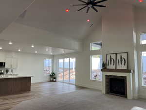 Living area featuring a ceiling fan, baseboards, light wood-style floors, a high ceiling, and recessed lighting