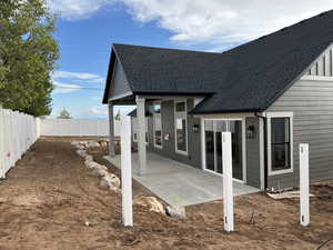 Back of property featuring a fenced backyard, a shingled roof, and a patio area