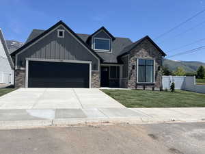 Craftsman-style home featuring an attached garage, roof with shingles, concrete driveway, board and batten siding, and a mountain view