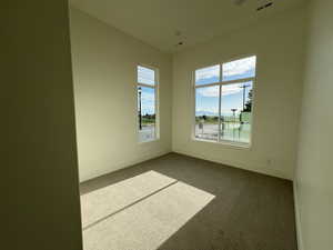 Unfurnished room with visible vents, baseboards, and dark carpet