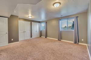 Large basement bedroom with two closets, carpet floors, and a textured ceiling