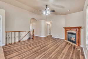 Unfurnished living room featuring lofted ceiling, ceiling fan, and wood-type flooring