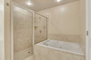 Primary Bathroom with shower with separate bathtub and a textured ceiling