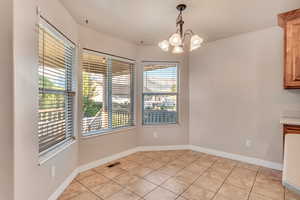 Unfurnished dining area with a notable chandelier and light tile patterned floors