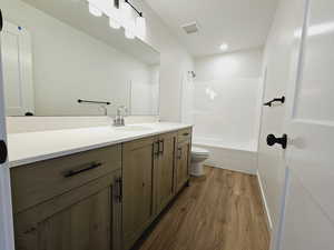 Full bathroom featuring shower / bath combination, toilet, hardwood / wood-style flooring, and vanity