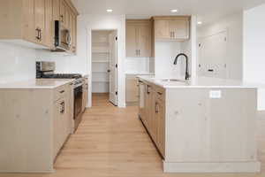 Kitchen featuring light brown cabinetry, a center island with sink, appliances with stainless steel finishes, and sink