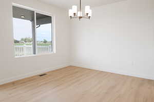 Unfurnished room featuring a notable chandelier and light hardwood / wood-style floors