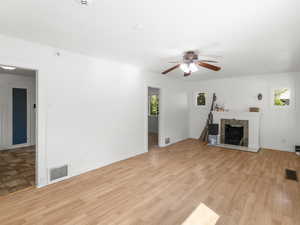 Unfurnished living room featuring light hardwood / wood-style flooring, ceiling fan, and a tiled fireplace