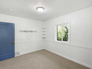 Empty room featuring a textured ceiling and carpet