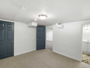 Carpeted empty room featuring a textured ceiling and sink