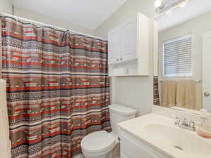 Bathroom with a shower with shower curtain, toilet, and vanity