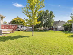 View of yard featuring central AC, a storage shed, and a deck